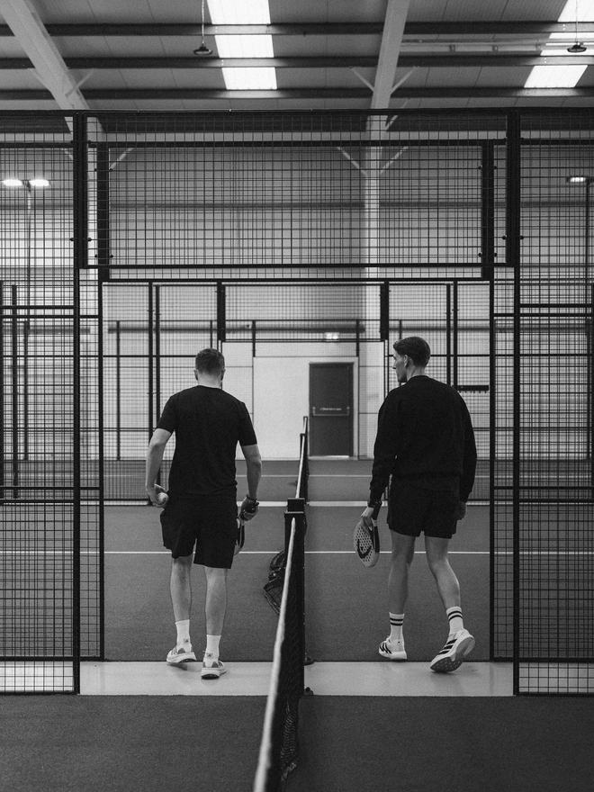 Two players walking onto a padel court
